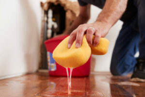 Man mopping up water from the floor with a sponge